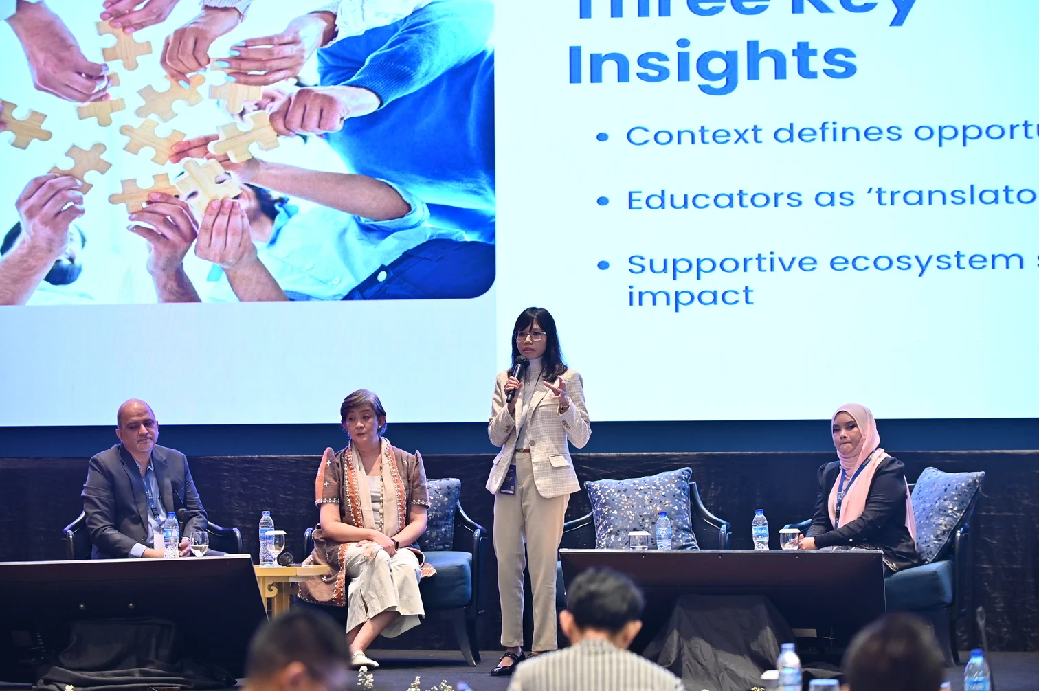 Panel on stage with a speaker presenting key insights